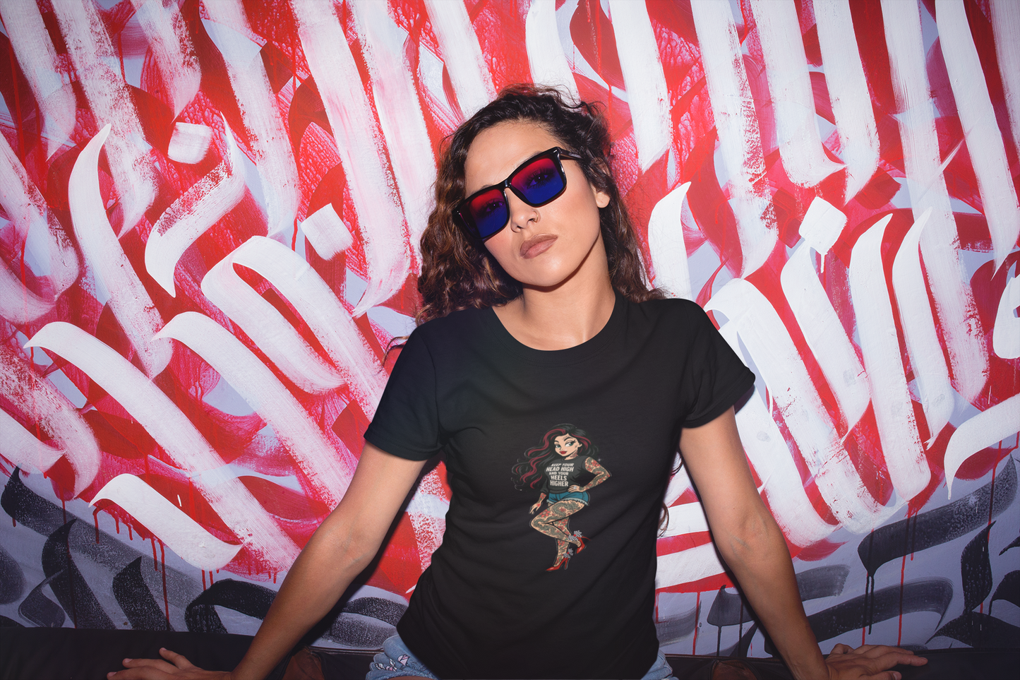 Person wearing a black t-shirt with a graphic design in front of a red and white abstract wall. The Bean Grind Streetwear